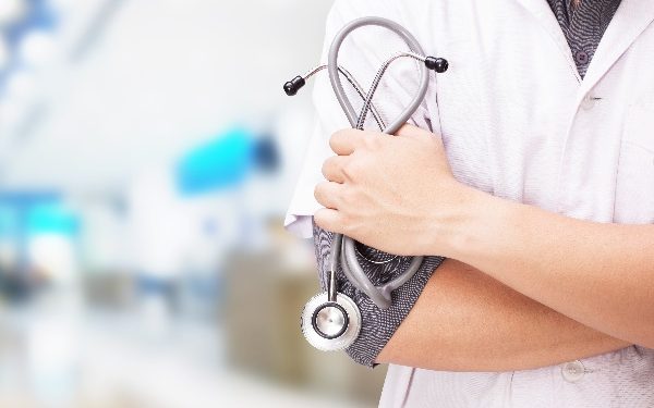 Doctor with a stethoscope in the hands and hospital background.